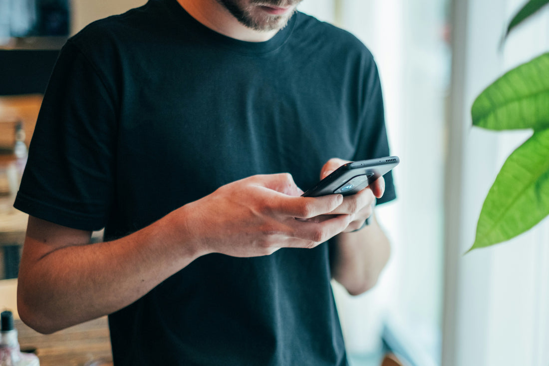 man in black shirt holding a smartphone and typing in restaurant